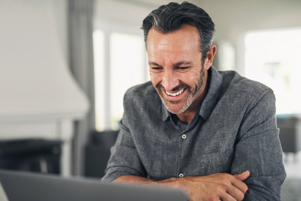 Man kijkt thuis lachend op laptop