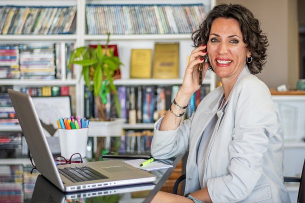 Knappe oudere vrouw aan de telefoon in haar eigen kantoor