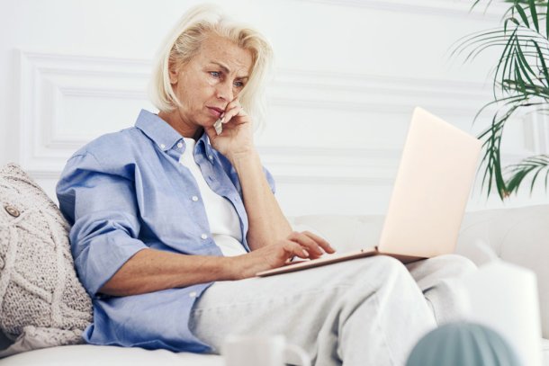 Vrouw op de bank zit op een computer te kijken