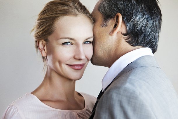 Man fluistert bij vrouw in het oor