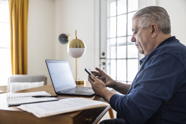 Corpulente man is thuis aan het werk achter zijn laptop