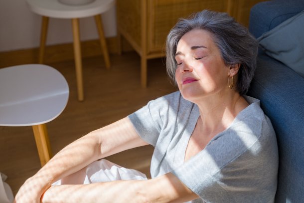 oudere vrouw zit binnen in de zon