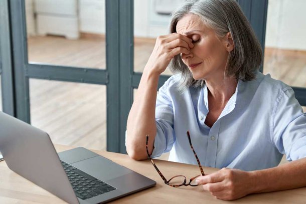 vrouw met vermoeide ogen achter laptop