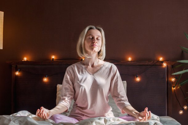 Vrouw doet yoga-oefening op bed voor het slapengaan