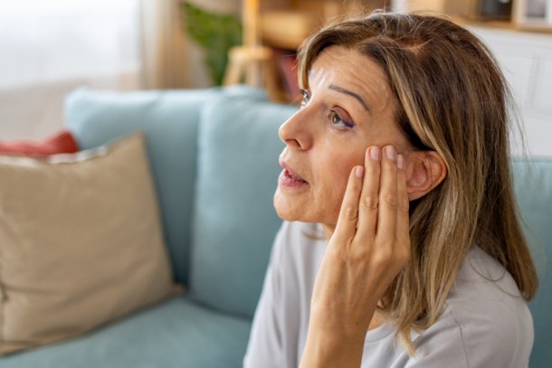 Vrouw met hand op haar oor, ze wordt gek van piep