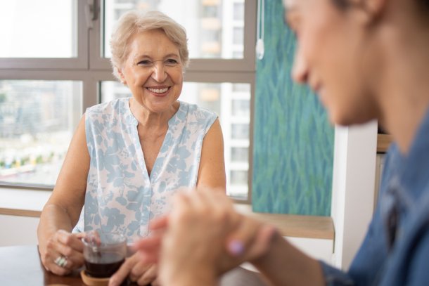 oudere vrouw drinkt koffie met mantelzorger