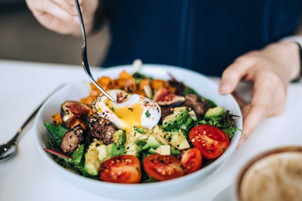 Vrouw eet salade met ei