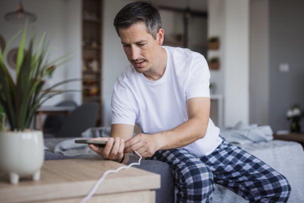 Man legt telefoon aan oplader