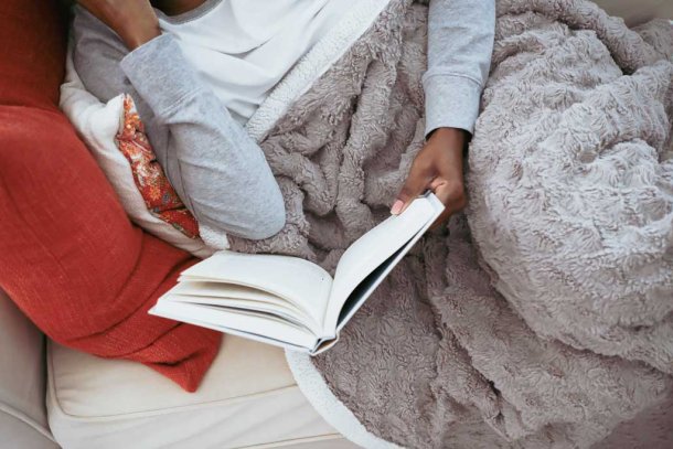 Vrouw met warmtedeken op de bank