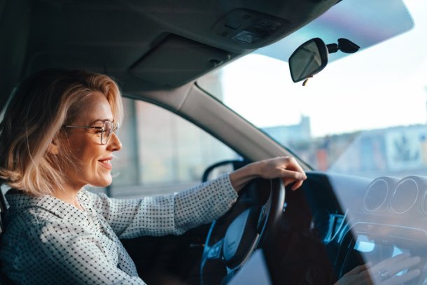Oudere vrouw achter het stuur van de auto, lachend