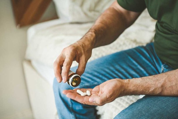 Man zit op rand van het bed neemt erectiepil