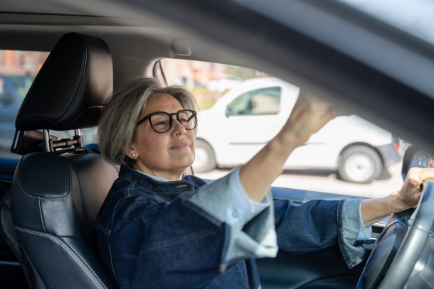 Vrouw zit in de auto en checkt haar uiterlijk