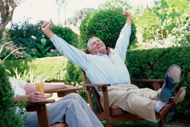 Man in zijn achtertuin juichend omdat hij met pensioen is