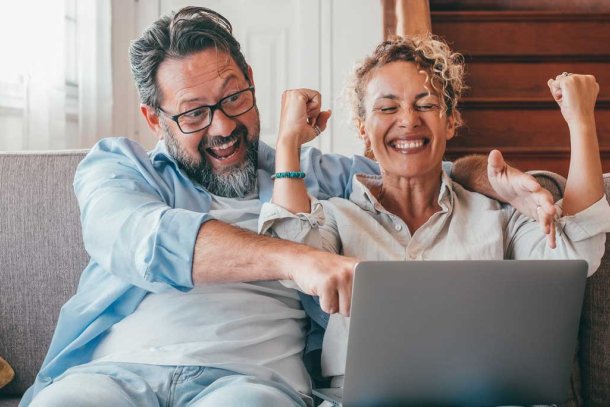 Vrouw en man zien dat ze de loterij gewonnen hebben op laptop
