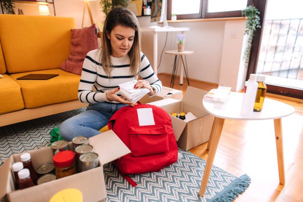 vrouw stelt noodpakket samen in de woonkamer