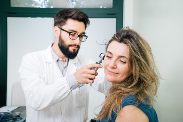 Oorarts kijkt in oor bij vrouw