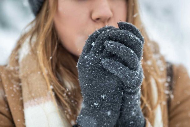 Vrouw heeft koude handen in haar handschoenen want het sneeuwt