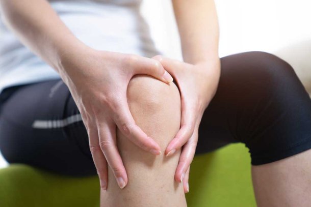 Vrouw met haar handen om haar pijnlijke knie