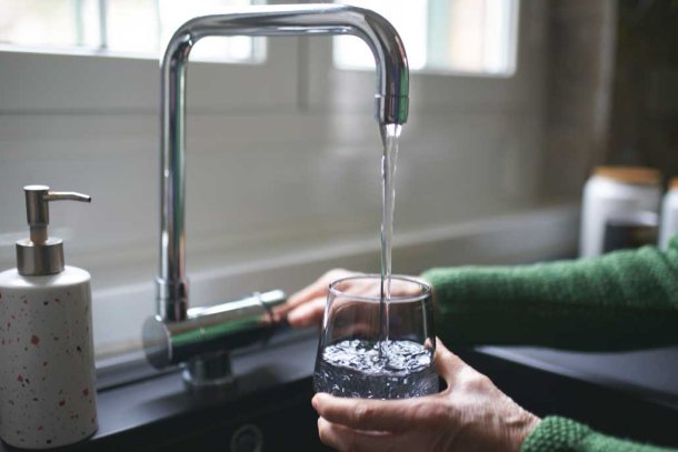 vrouw vult glas water aan kraan