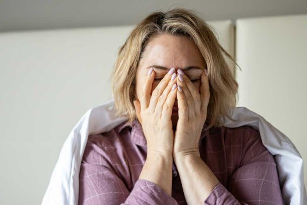 Vrouw zit vermoeid op bed na een slechte nacht slapen