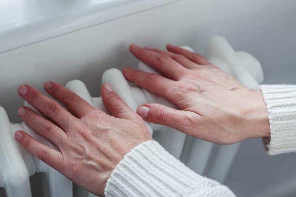 Vrouw warmt haar handen aan de verwarming