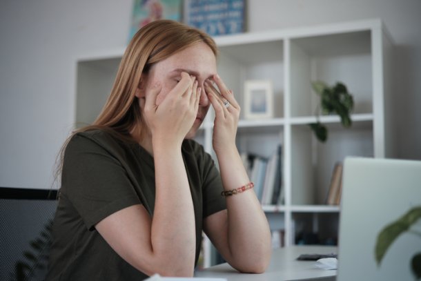 Vrouw met handen voor gezicht door computerproblemen