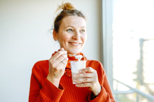lachende vrouw eet yoghurt