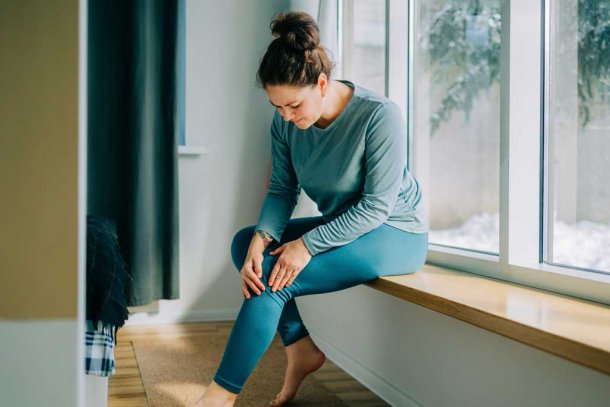 Vrouw voelt aan haar knie die zeer doet