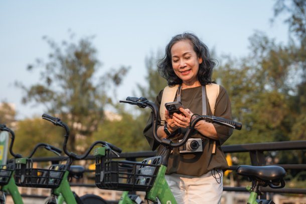 Oudere dame checkt haar smartphone bij fietsenstalling