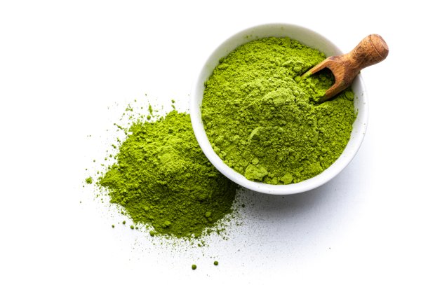 Matcha in een potje met een houten lepel op een witte achtergrond