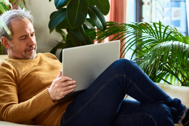 Man op de bank met laptop op schoot