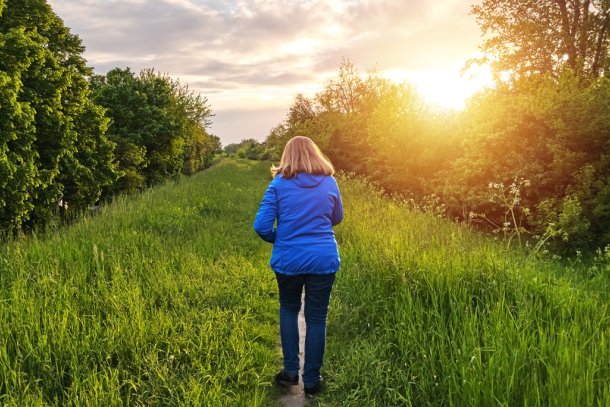 Vrouw loopt over dijk in het opkomende zonnetje