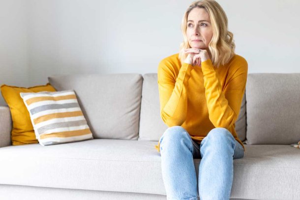 Vrouw zit op de bank en denkt na