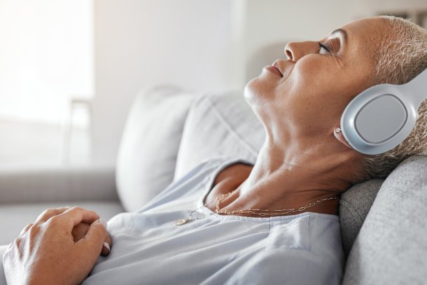 Vrouw ligt op de bank en luistert naar een podcast