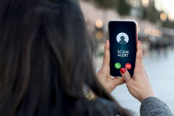 Vrouw met tekst Scam Alert op haar smartphone, phishing en oplichting
