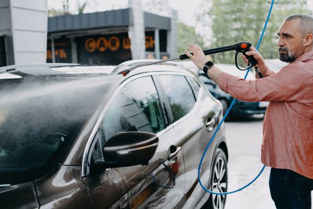 oudere man wast zijn auto bij wasbox