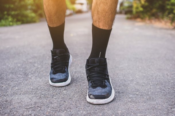 Man op gympen loopt op straat